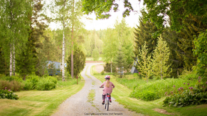 Lapsi ajaa pyörällä Kommeen Kurjen pihatiellä